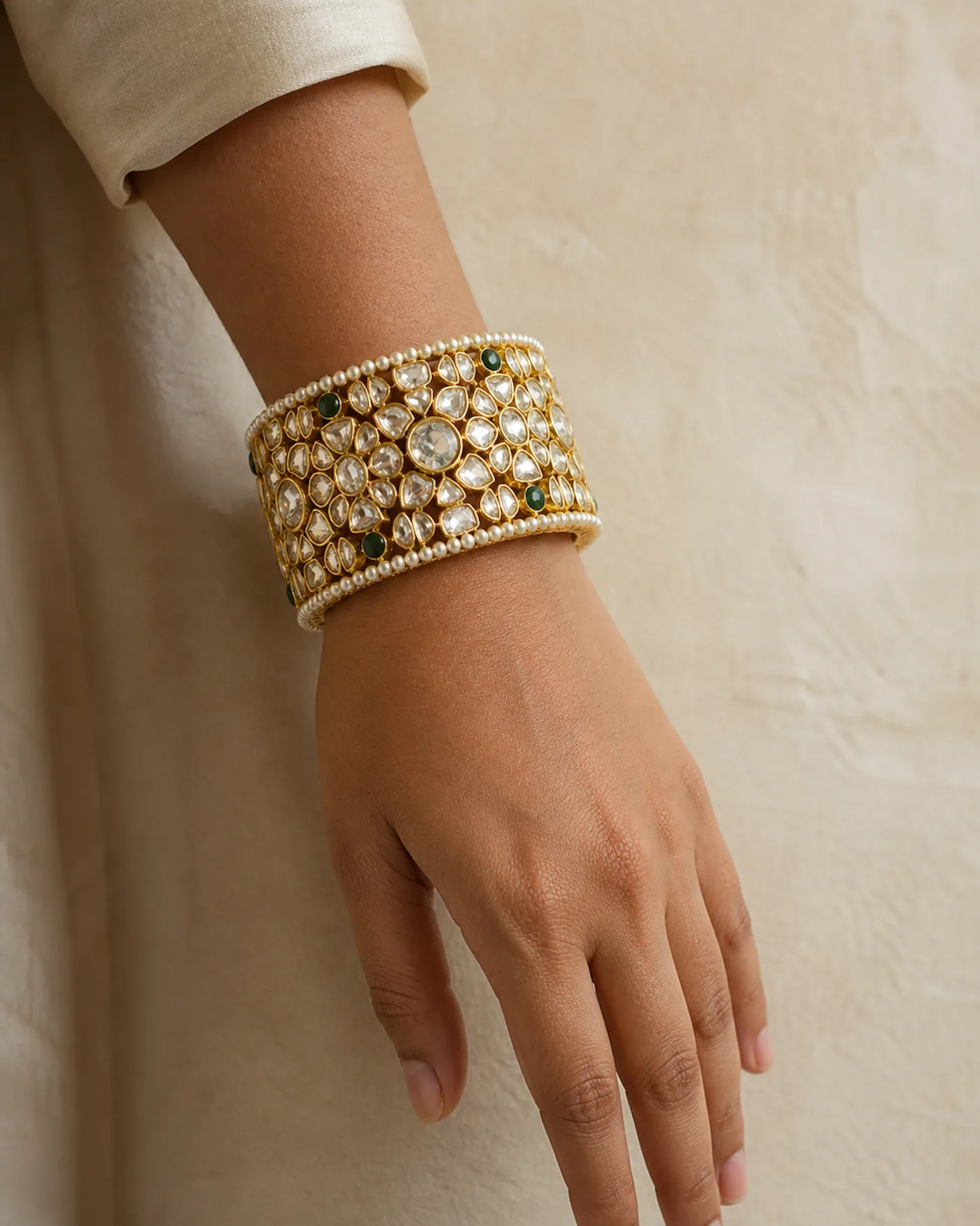 A wide jadau kangan set with uncut polki, worn on the wrist