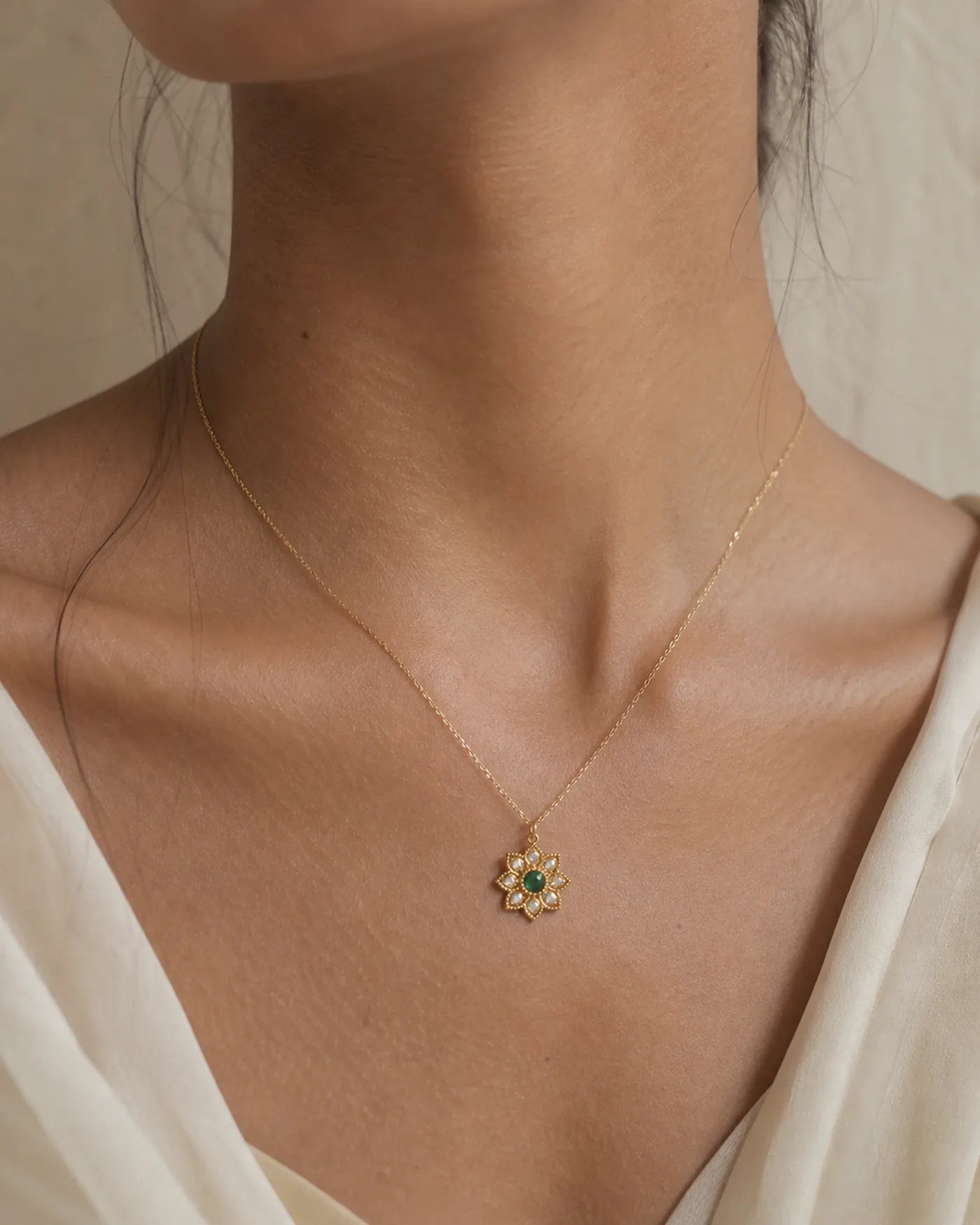 The pendant worn at the throat on a fine chain, showing its everyday scale