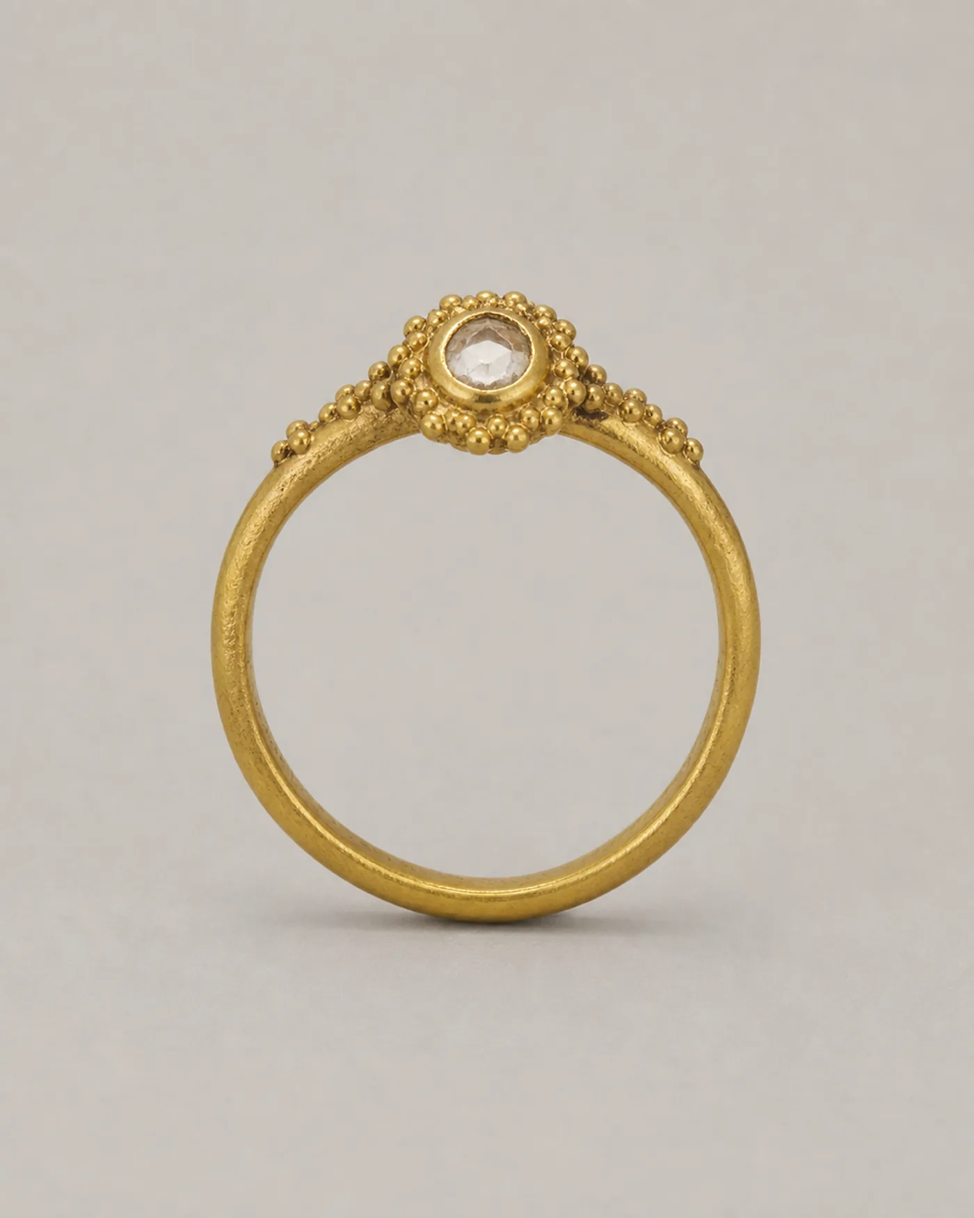 Slim gold ring with one uncut polki diamond closed in a kundan bezel, ringed with granulation